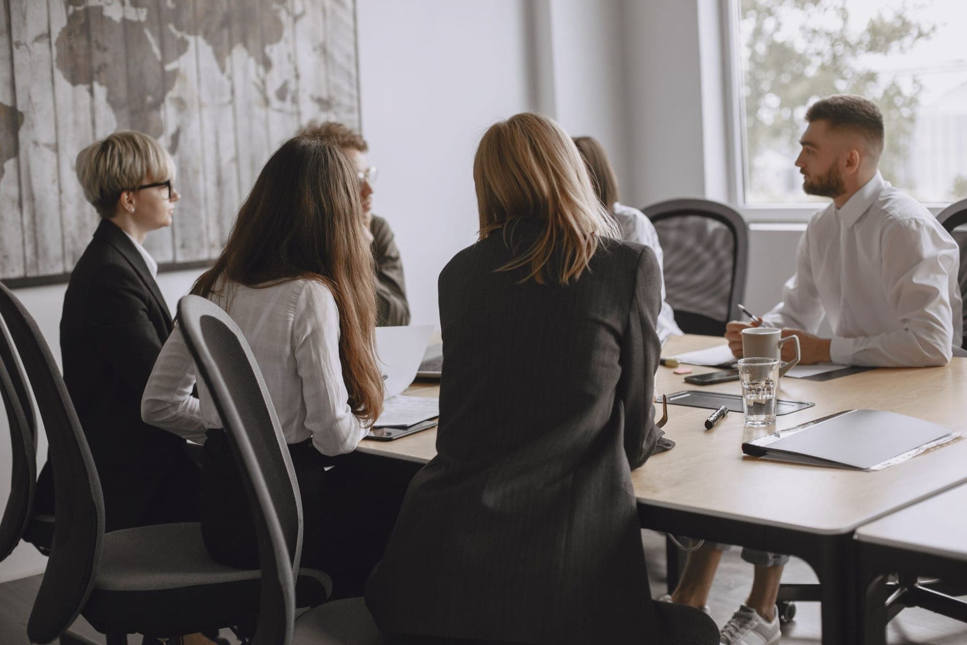 Equipe reunida em volta de uma mesa com documentos, conversando sobre um projeto